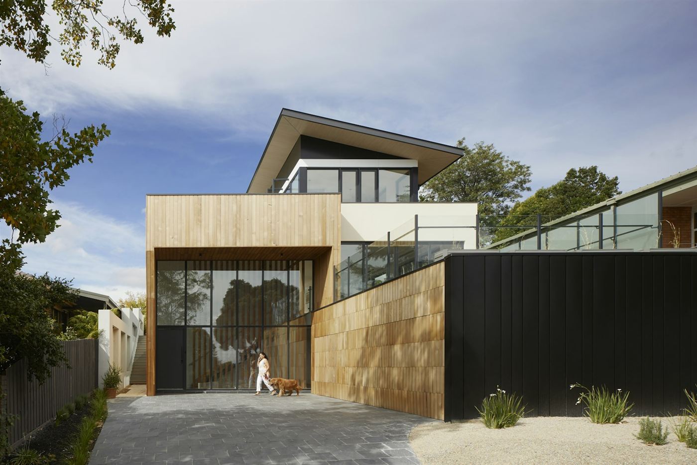 Moderne woning met houten gevel, zwarte schutting en grind voor de deur